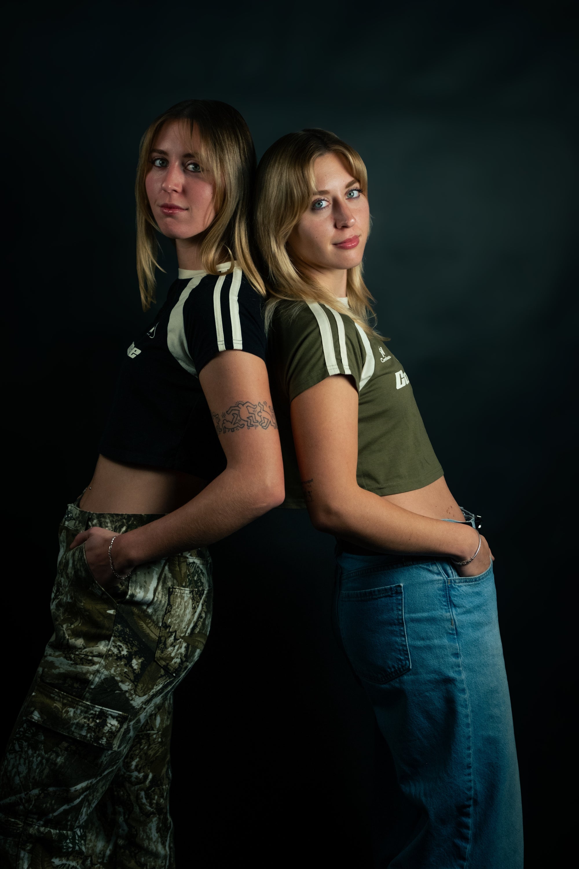Two women wearing matching green and white sports tops against a dark background
